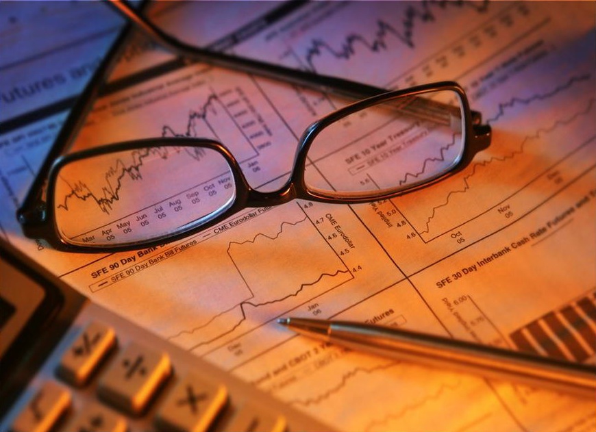 glasses on charts with pen and calculator representing analysis